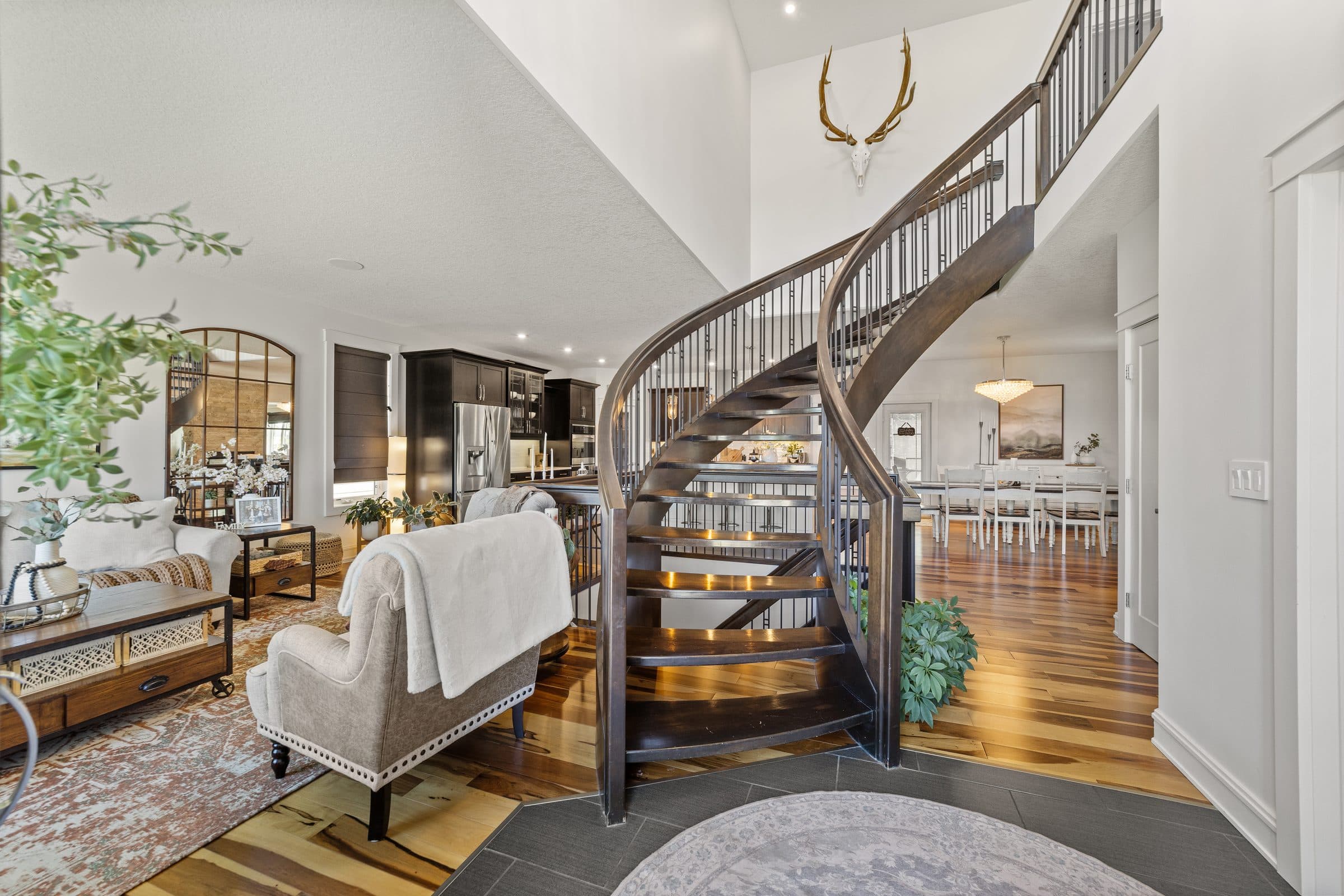 Curved dark wood staircase rising beside an open living and dining area